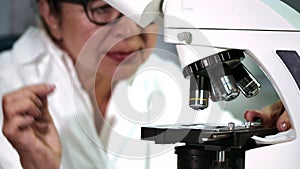 Senior female scientist working on a microscope at her lab