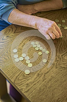 senior female sitting miserably at the table at home and counting coins photo