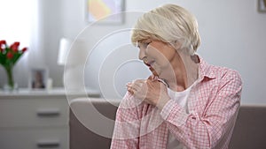 Senior female suffering from pain massaging shoulder, joint disease, arthritis