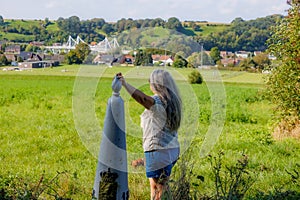 Senior female tourist standing at border marker between Belgium and Holland