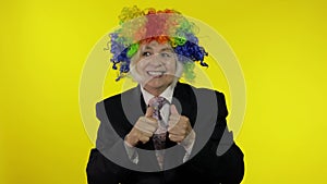 Senior female woman in business suit wears clown wig, begin working and smiling