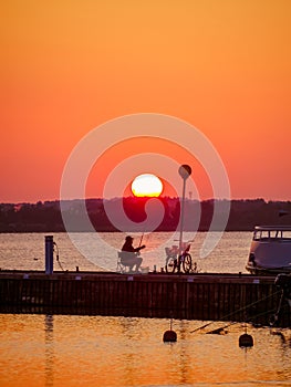 Senior fisherman fishing at dawn on a pier, real candid people