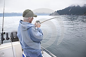 Senior fisherman reeling in a fish near Seward, Alaska