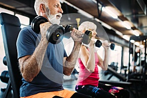 Senior fit man and woman doing exercises in gym to stay healthy