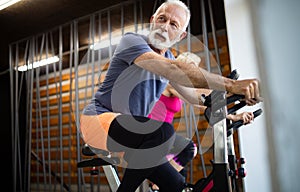 Senior fit man and woman doing exercises in gym to stay healthy