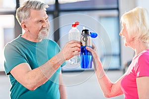 Senior fitness couple holding bottles with water gym