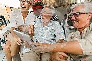 Senior friends with eyeglasses using digital tablet, having fun
