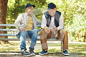 Senior friends, funny and relax at park, talking and bonding outdoor in retirement. Happy elderly men sitting together