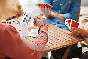 Senior friends, hands or playing card games on wooden table in fun activity, social bonding or gathering. Group of