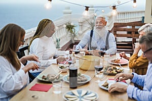 Senior friends having fun at patio dinner party - Focus on hipster male face