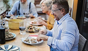 Senior friends having fun at patio dinner party - Focus on right male face