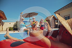 Senior friends having fun playing with water guns at the swimming pool