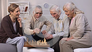 Senior friends playing chess at home, leisure time in good company, togetherness
