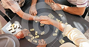 Senior Friends Shaking Hands Winning Game Of Domino