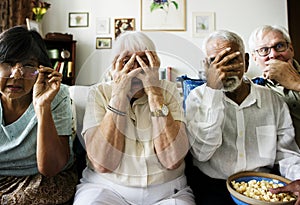 Senior friends sitting on couch with horrified reaction