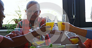 Senior friends toasting glasses of juice on dining table 4k