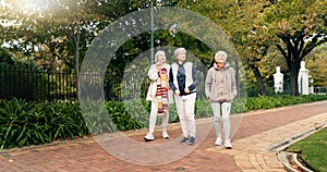 Senior friends, walking and talking together on an outdoor path to relax in nature with elderly women in retirement