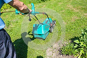 Senior gardener mowing his green lawn in garden. Man working on lawn cutting grass with lawn mower. man is mowing grass