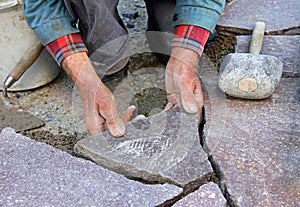 senior gardener paving natural stone terrace, professional precision work