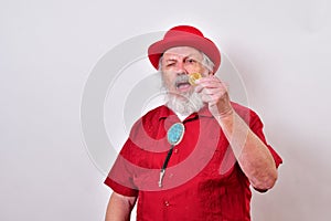 Senior gentleman all dressed in red is inspecting a coin