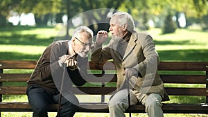 Senior gentlemen talking to his hearing impairment old friend, health problems