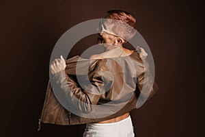 Senior ginger woman smiling while posing in leather jacket