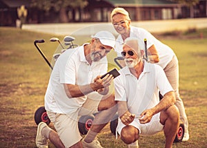 Senior golfers on court. Two men using smart phone