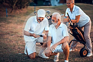 Senior golfers on court. Two men using smart phone