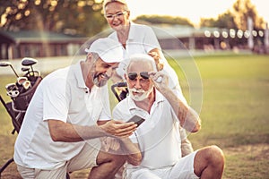 Senior golfers on court. Two men using smart phone