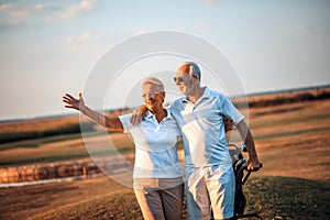 Senior golfers on golf course.  Woman waving to somebody