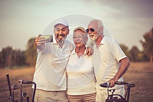 Senior golfers using phone and taking self portrait.