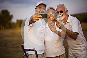 Senior golfers using phone and taking self portrait.