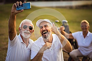Senior golfers using phone and taking self portrait.