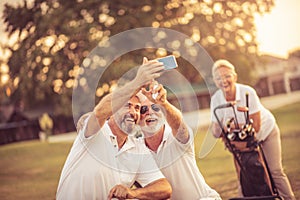 Senior golfers using phone and taking self portrait.