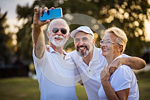 Senior golfers using phone and taking self portrait.  Time for memories