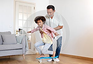 Senior Grandpa Teaching Grandson To Ride A Skateboard At Home