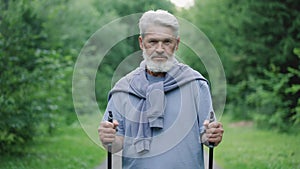 Senior gray beard old man nordic walking poles portrait. Hiker grandfather face.