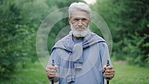 Senior gray beard old man nordic walking poles portrait. Hiker grandfather face.