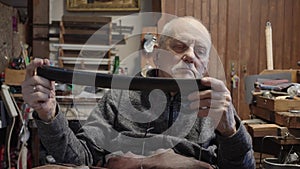 Senior gray haired male master in a wheelchair working at his workshop restoring japanese sword