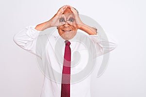 Senior grey-haired businessman wearing elegant tie over isolated white background doing ok gesture like binoculars sticking tongue