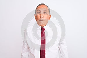 Senior grey-haired businessman wearing elegant tie over isolated white background making fish face with lips, crazy and comical