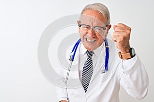 Senior grey-haired doctor man wearing stethoscope standing over isolated white background angry and mad raising fist frustrated