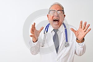 Senior grey-haired doctor man wearing stethoscope standing over isolated white background celebrating mad and crazy for success