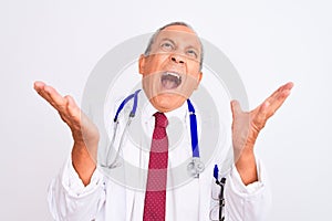 Senior grey-haired doctor man wearing stethoscope standing over isolated white background crazy and mad shouting and yelling with