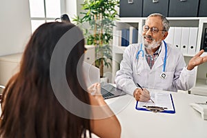 Senior grey-haired man doctor and patient having medical consultation at clinic