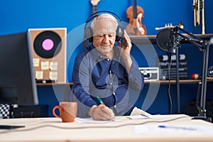 Senior grey-haired man musician composing song at music studio