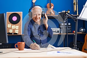 Senior grey-haired man musician composing song at music studio