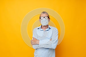 Senior grey-haired man protective mask health yellow background