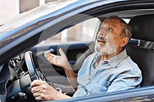 Senior grey-haired man stressed driving car at street