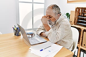Senior grey-haired man stressed working at office
